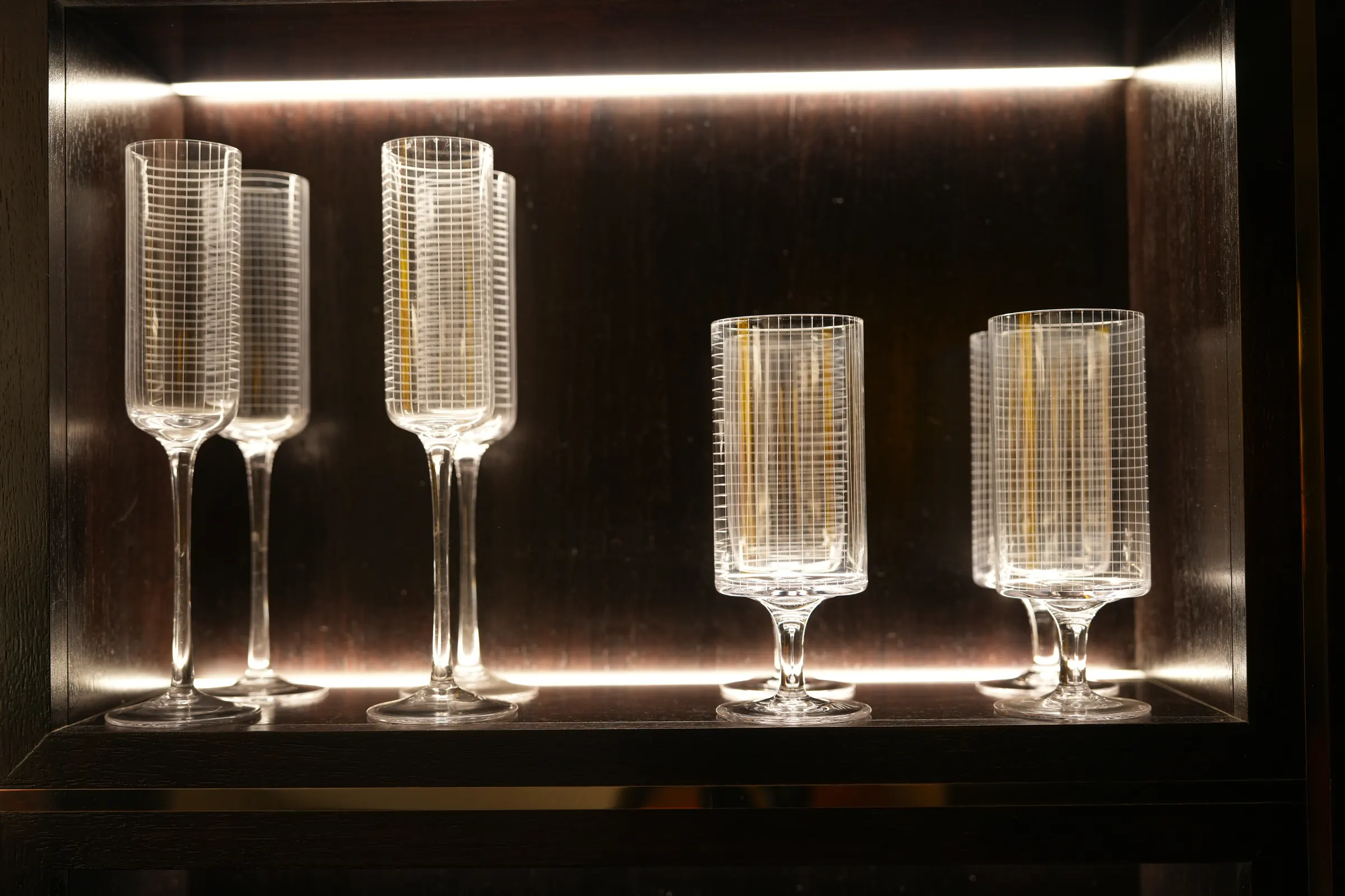 Cut-crystal glassware on a lit shelf