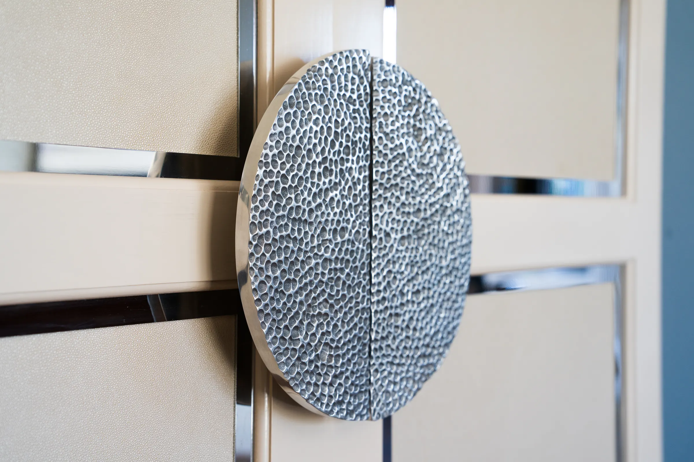 Hammered metal handle on a shagreen-panelled door