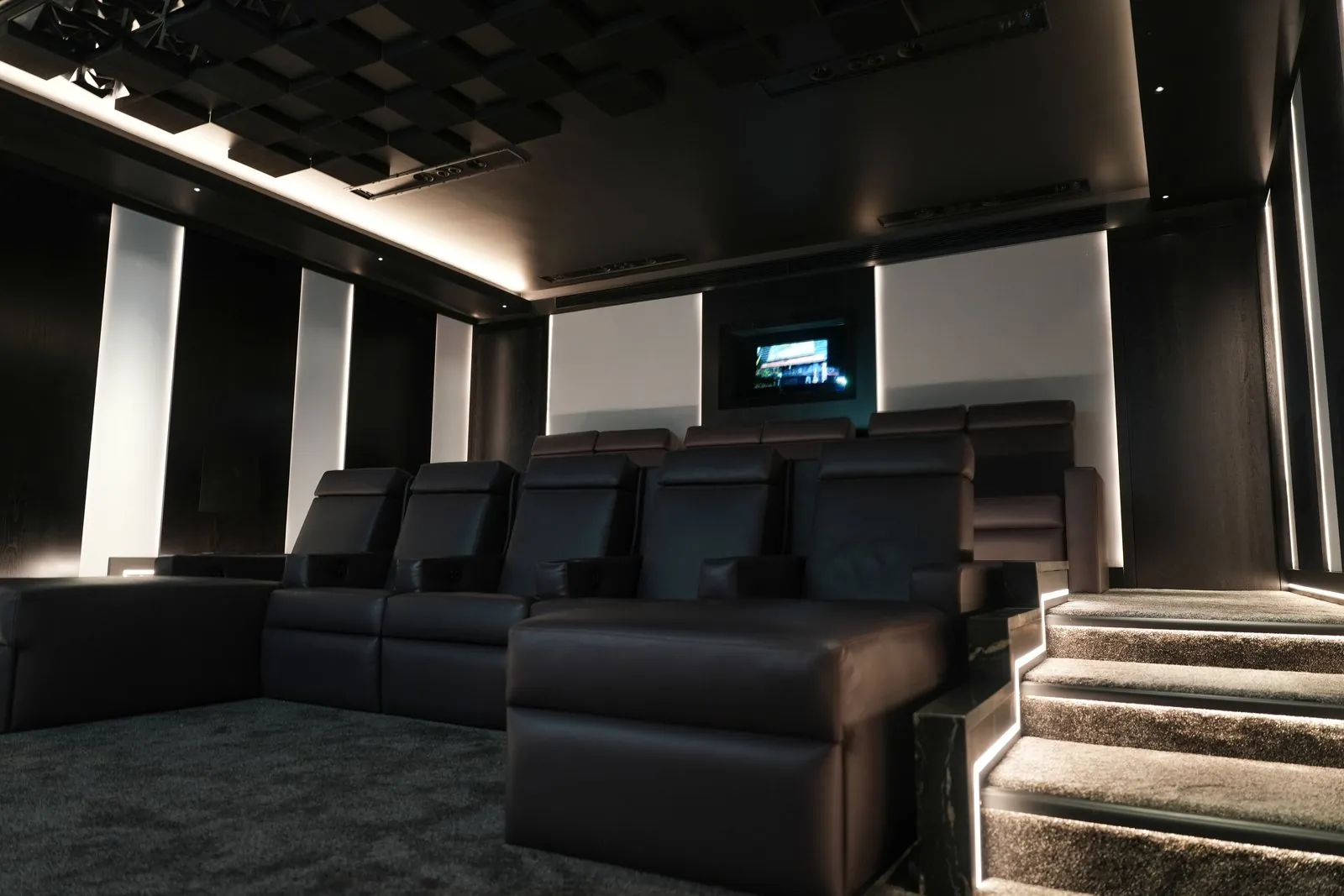 A private cinema with leather recliners, backlit fabric panels and a sculpted acoustic ceiling