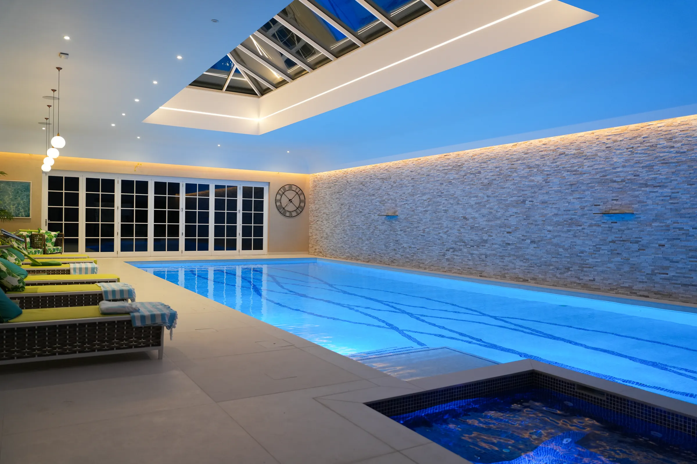 The indoor swimming pool under a rooflight, lit in blue