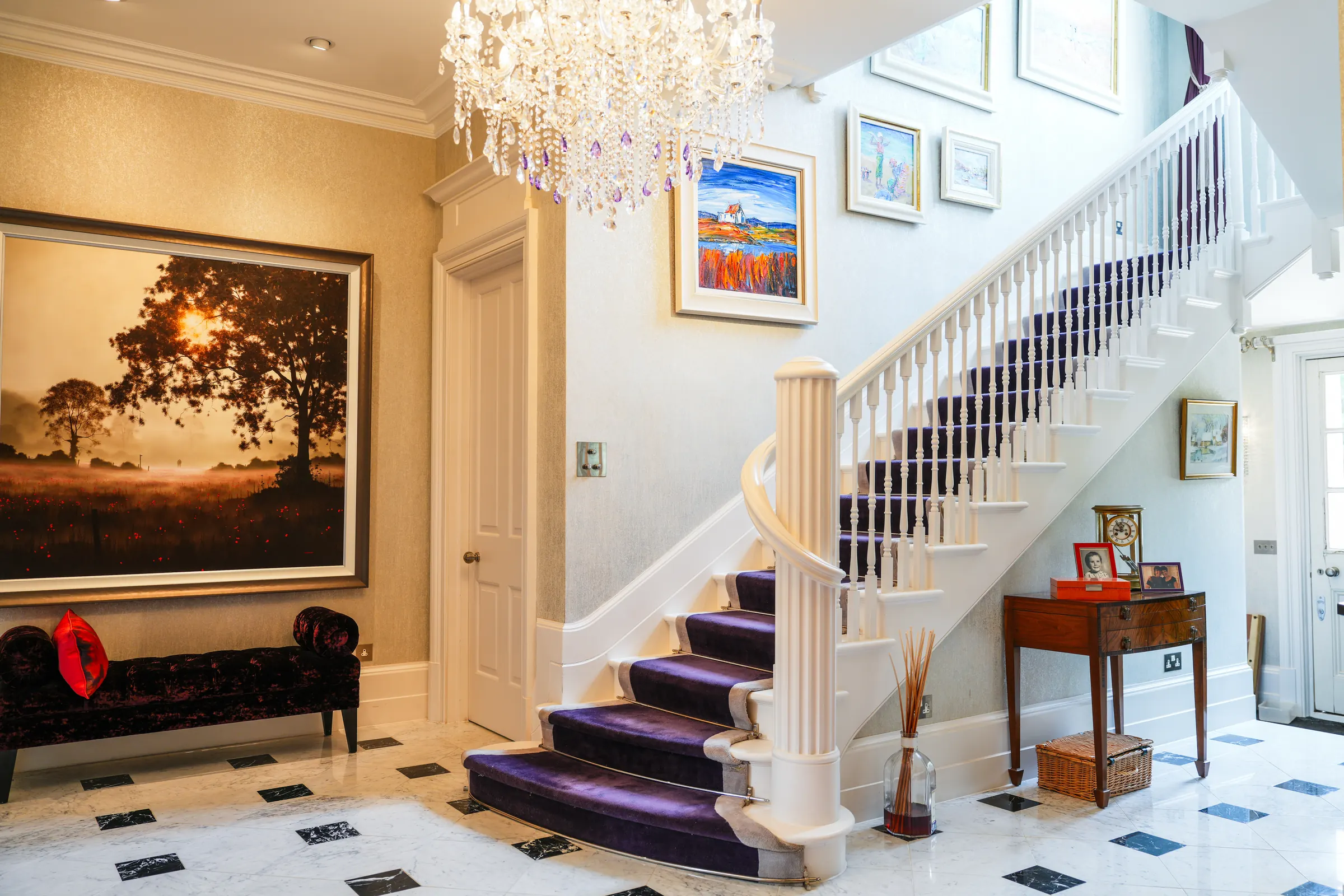The entrance hall and staircase under a crystal chandelier